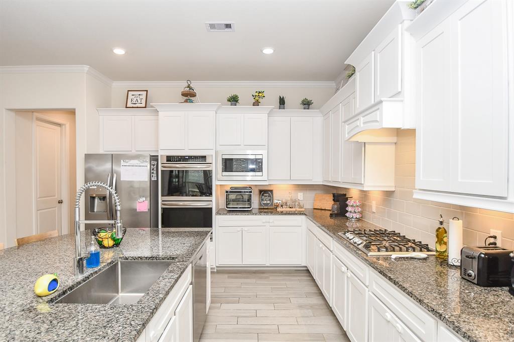 Granite countertops, light and bright kitchen paint, and an impressive backsplash combine to create a chef\'s dream in this kitchen.