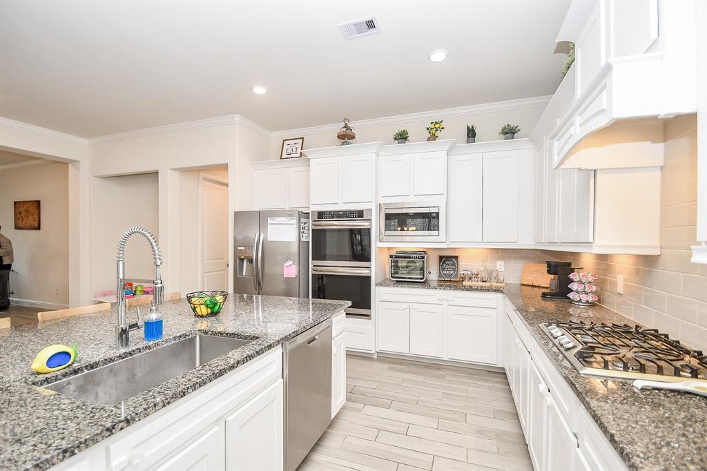 The beautiful tile floors, recessed lighting, tall cabinets, and granite countertops not only enhance the aesthetic appeal but also elevate the functionality of this kitchen.