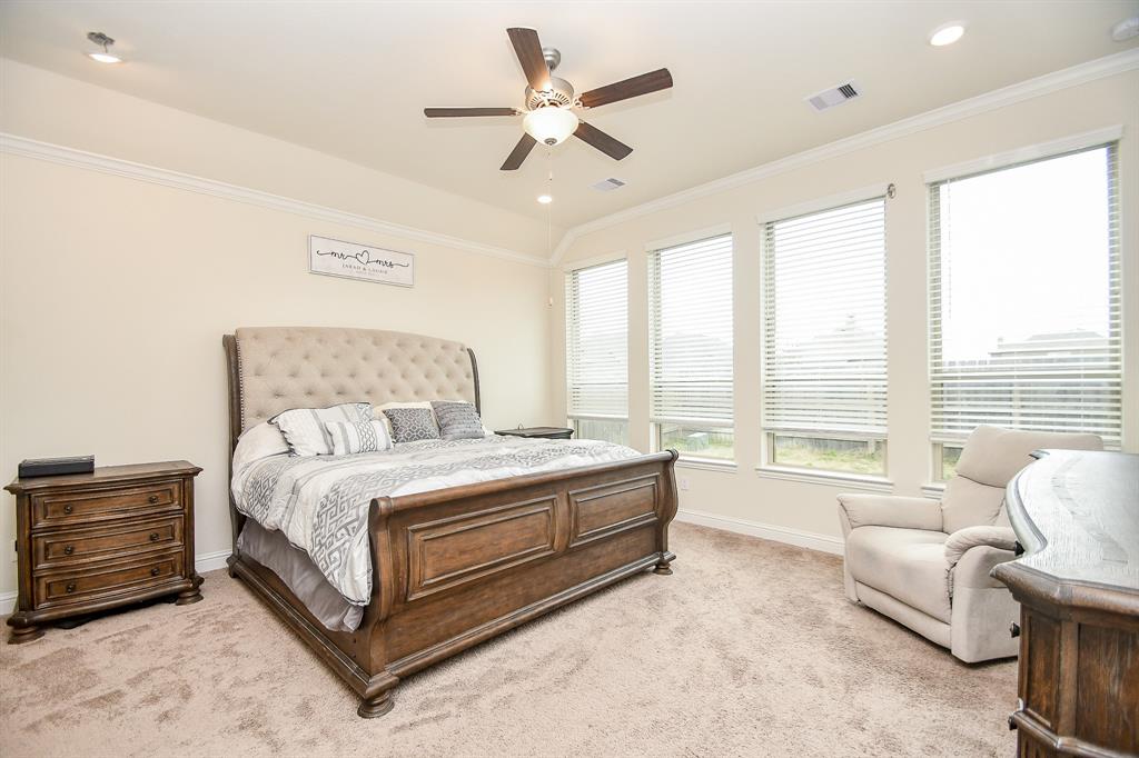 The primary bedroom is bathed in natural light streaming through beautiful windows, further accentuated by its tall ceilings.