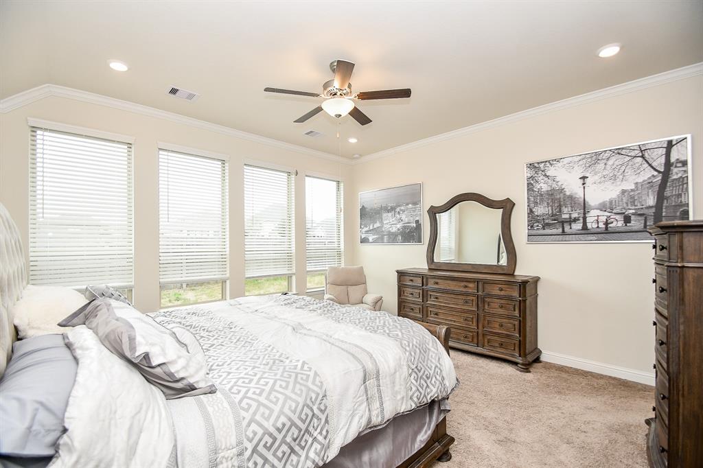 With its tall ceilings, recessed lighting, and floor-to-ceiling windows, this primary bedroom boasts the epitome of luxury and comfort.