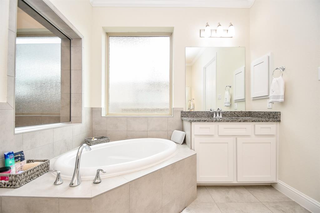 Escape to tranquility with the large soaking tub and vanity, transforming this bathroom into a serene oasis after a long day.