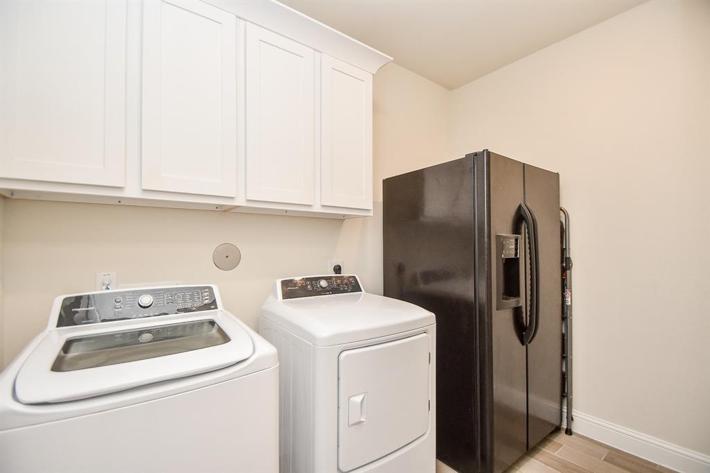 No shortage of space in this large utility room, offering ample room for a refrigerator or freezer, along with convenient cabinet storage.