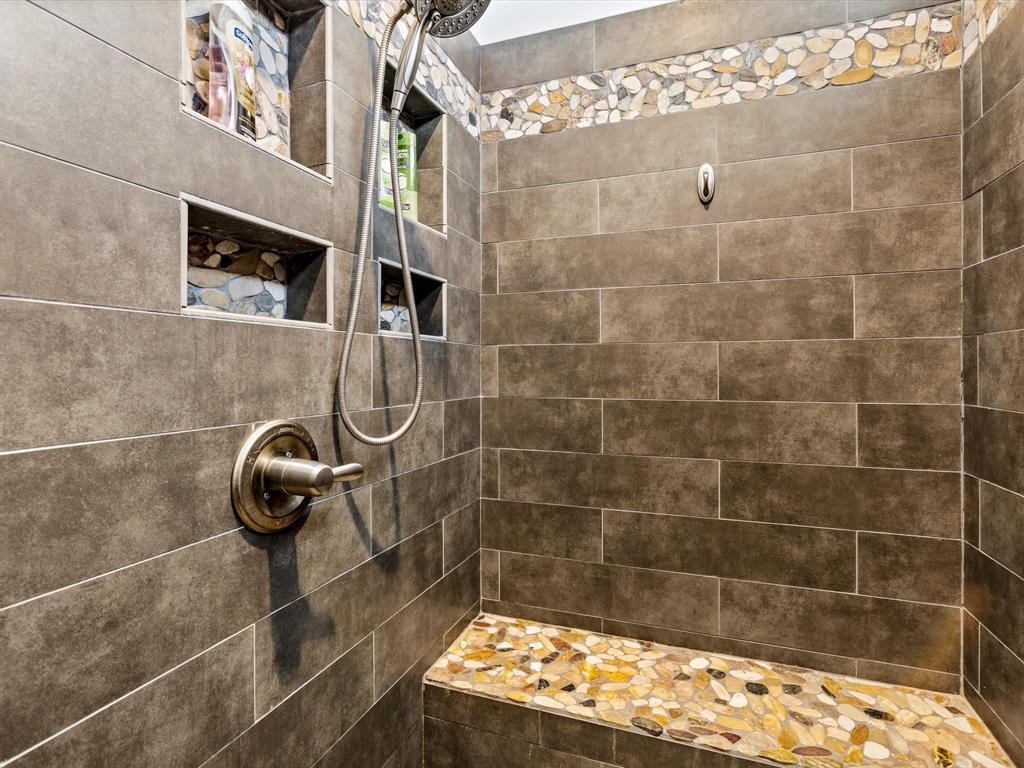 Beautiful walk-in shower with a sitting bench and insets for your bath items.