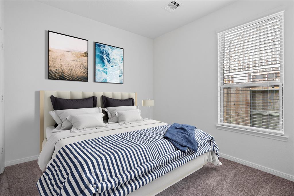 Secondary bedroom features plush carpet, neutral paint and a large window with privacy blinds.