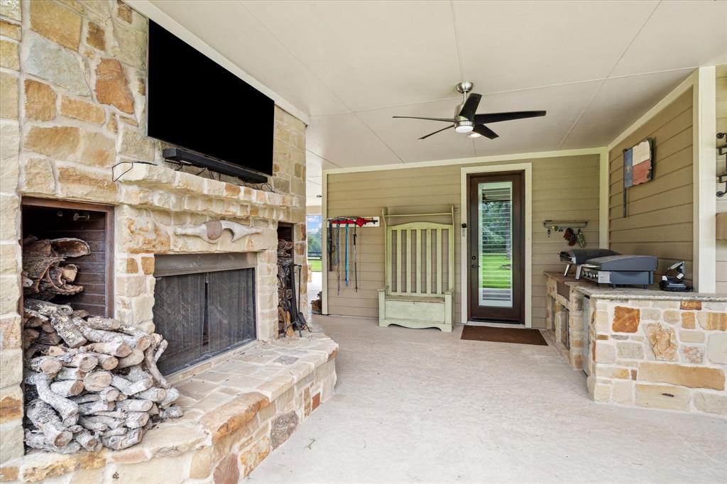 The outdoor kitchen area features a full size stone fireplace, big screen TV, with room for an outdoor grill, pizza oven and other cooking accoutrements