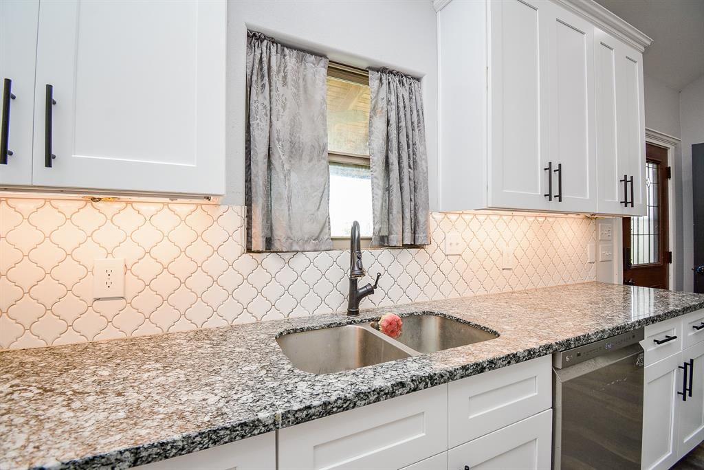 Creamy granite countertops surround every surface of this completely workable kitchen; with delicate, contrasting tile backsplash. A window over stainless steel kitchen sinks is always a bright feature.