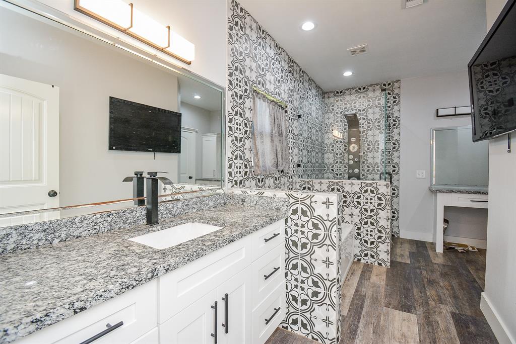 This delightful tile motif welcomes and warms your primary ensuite bath, with a lush granite topped counter, wall wide mirror; separate tub and walk-in shower.