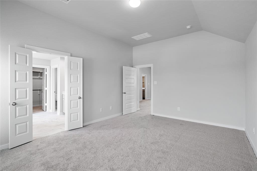 Another view of the primary bedroom showcasing the double door entry into the primary bathroom.