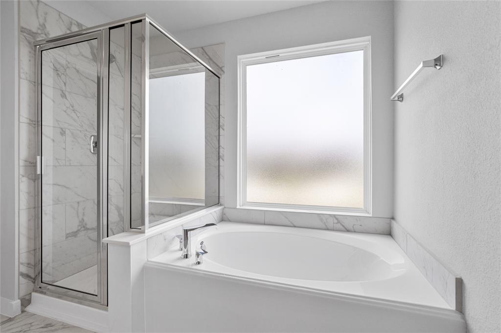 This master bathroom is definitely move-in ready! Featuring dark framed walk-in shower with tile surround, separate garden tub for soaking after a long day with custom tile detailing, spacious walk-in closet with shelving, high ceilings, custom paint, sleek and dark modern finishes!