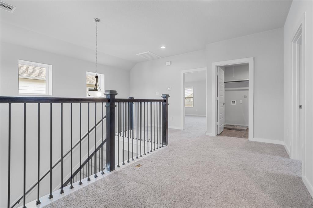 Come upstairs to the loft area showcasing the gorgeous railing, staircase, beautiful hanging pendant lighting plenty of windows to allow natural light, plush carpet, high ceiling, and custom paint!