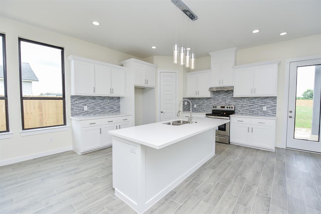 Gorgeous quartz countertops, complemented by delicate pendant lighting and ample natural light throughout this open space.