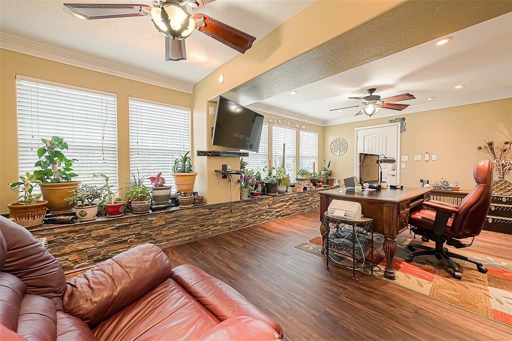 This room is multi-functional. This owner uses it as an office, but alternatively, it can be used as the living room for the guest apartment. Recent luxury vinyl plank flooring and two great ceiling fans finish off the room. The door shown in the background is an exit door leading out to the covered parking area.