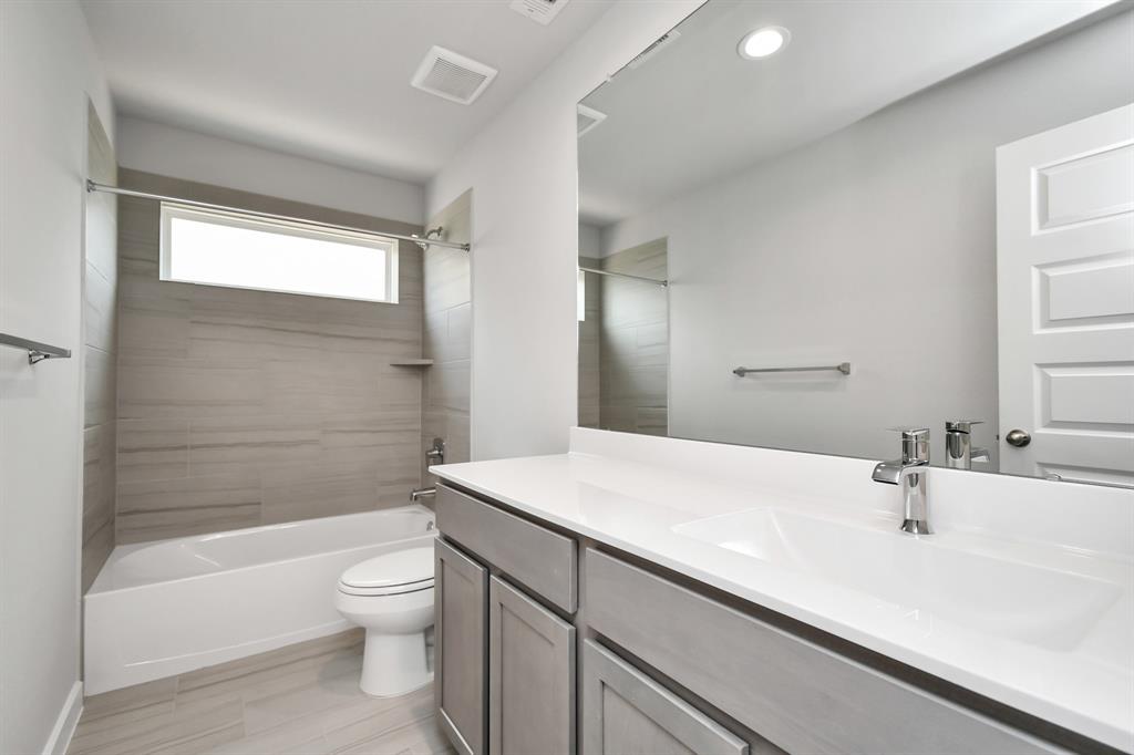 Experience sophistication in the secondary bathroom, where tile flooring complements a bath/shower combo with tile surround. Light wood cabinets complete with a beautiful light countertop, enhances the space for a truly inviting ambiance.