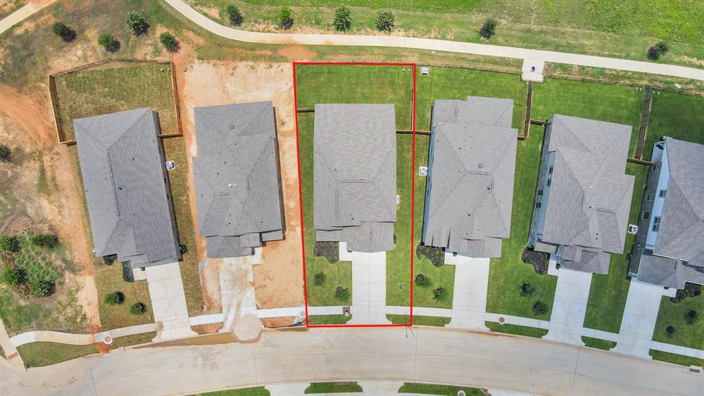 An aerial view of a spacious subdivision lake lot, highlighting a well-maintained yard and a fully fenced perimeter, offering both privacy and expansive outdoor space.