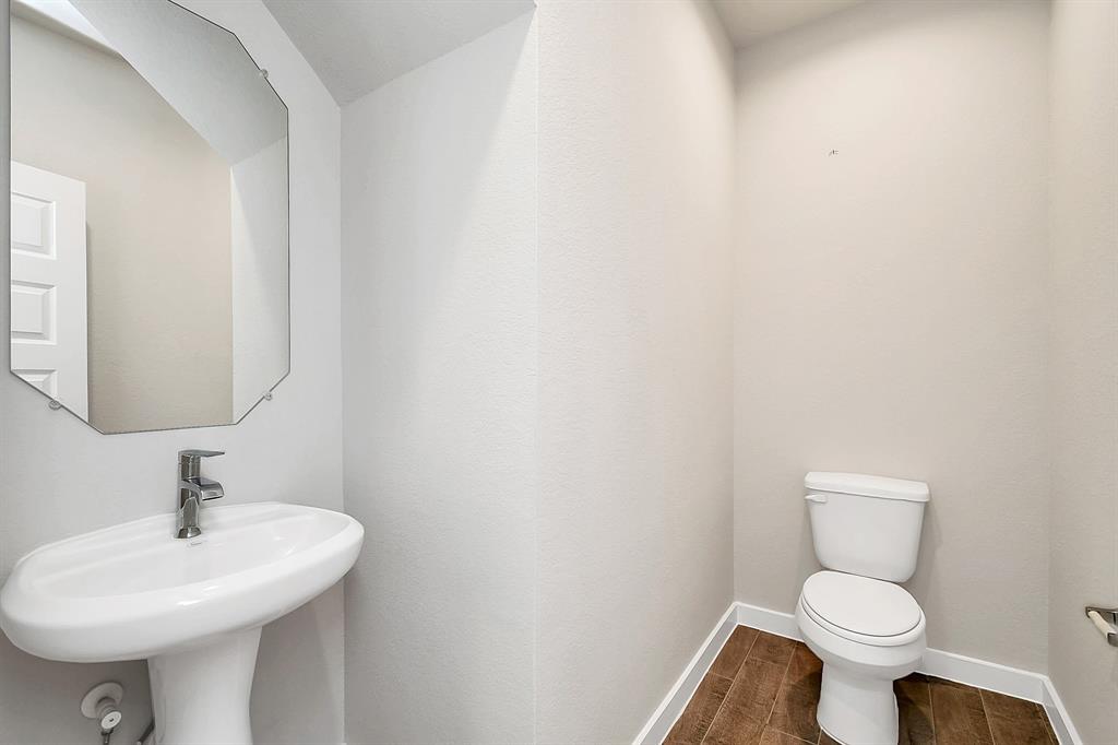 This half bathroom features a stylish pedestal sink, modern hardware, and bright recessed lighting, creating a sleek and inviting space.