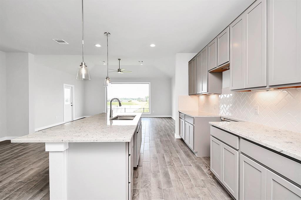 This spacious kitchen features high ceilings, light stained wood cabinets, granite countertop, SS appliances (to be installed), modern tile backsplash and recessed lighting.