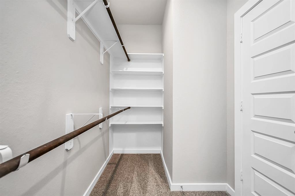 Expansive walk-in closet, adorned with high ceilings and luxurious carpet.