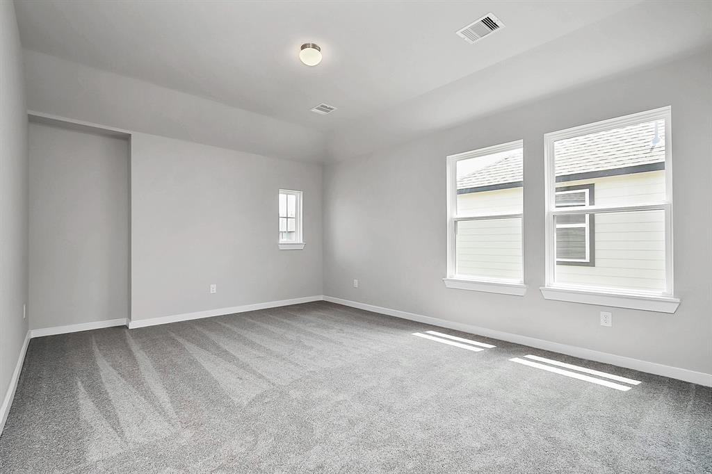 Secondary bedroom features plush carpeting, large windows that let in plenty of natural light, bright paint, and spacious closets.