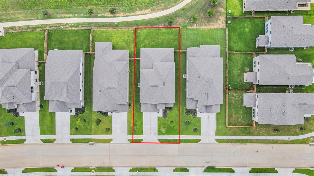 An aerial view of a spacious subdivision lake lot, highlighting a well-maintained yard and a fully fenced perimeter, offering both privacy and expansive outdoor space.