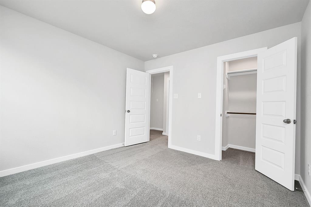 Secondary bedroom features plush carpeting, large windows that let in plenty of natural light, bright paint, and spacious closets.