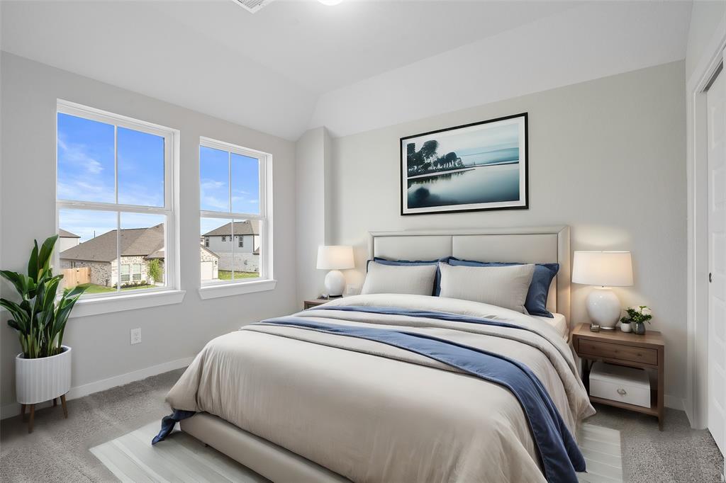 Secondary bedroom features plush carpet, custom paint, ceiling fan with lighting and a large window with privacy blinds.