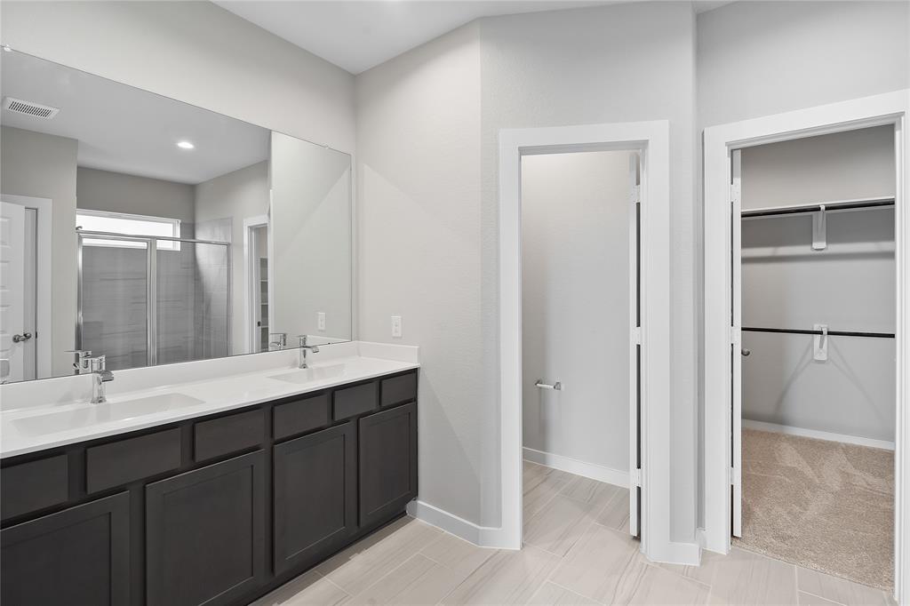 This primary bathroom is definitely move-in ready! Featuring dark stained cabinets with light countertops, spacious walk-in closet with shelving, high ceilings, custom paint, sleek and dark modern finishes.