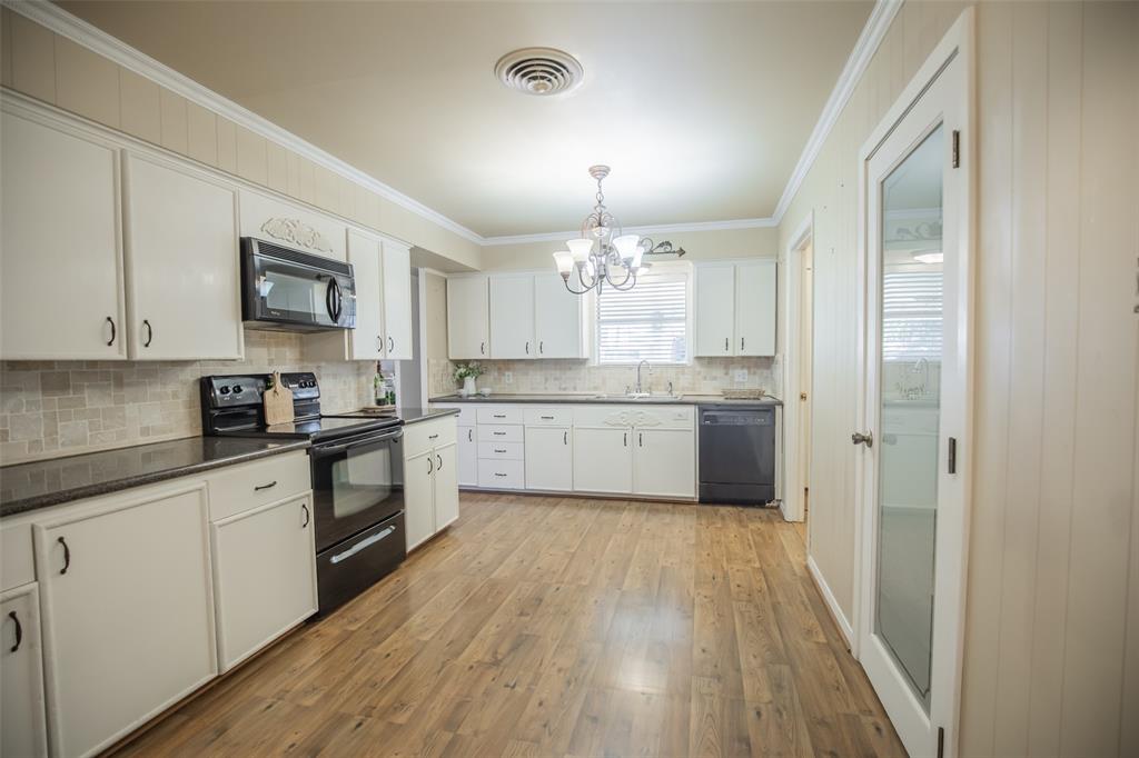 Timeless white cabinetry, granite counters, tumbled tile backsplash and engineered wood floors are right on trend in this kitchen.