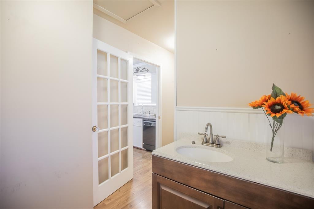 Pretty glass french door separates the laundry room from the kitchen in style. Laundry room cabinet, sink and faucet are prety and functional. And the wainscoting on the wall are a decorative touch.