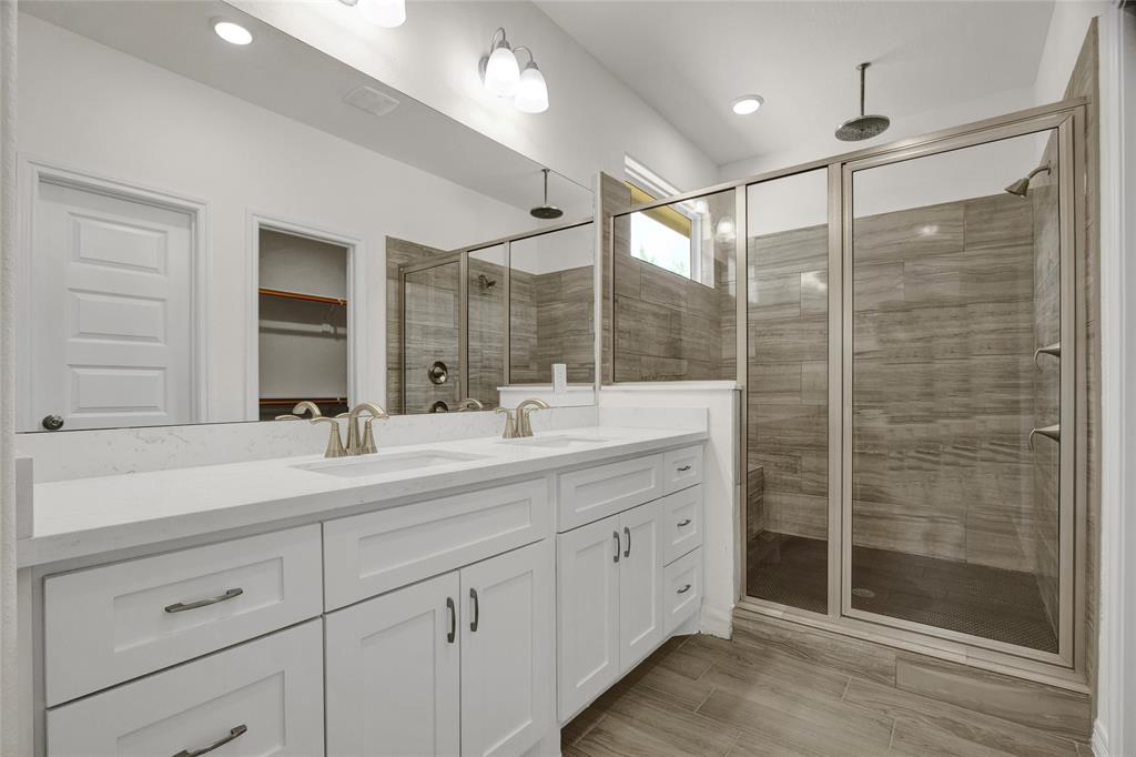 Primary bathroom with dual vanities Nice size shower with glass door