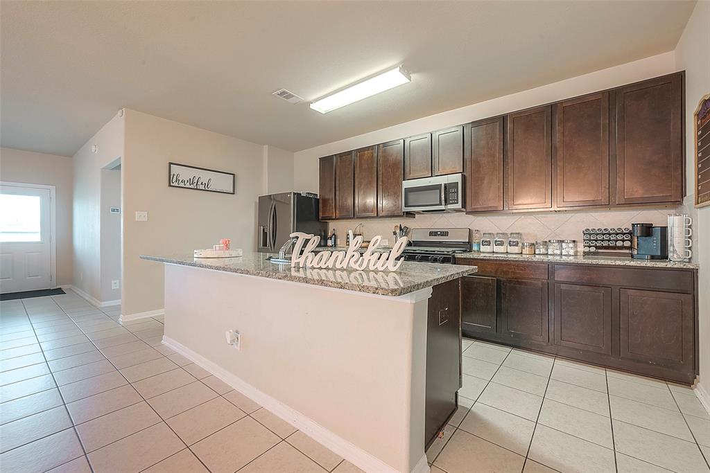 Modern kitchen with a spacious island and brown cabinets, perfect for meal prep. The island offers additional prep space and can double as a serving bar with additional storage below.