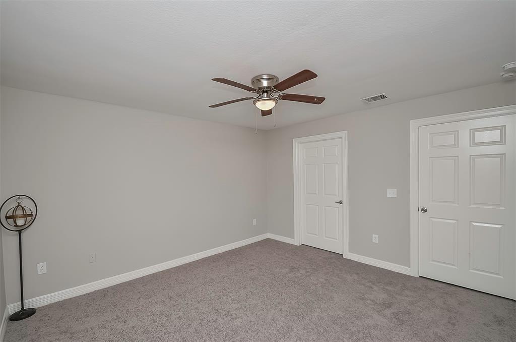 A modern bedroom with a ceiling fan and a view of the outside through a window.