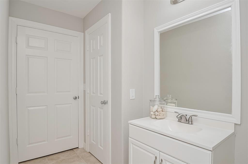 A clean, minimalistic bathroom with a white vanity, sink, large mirror, and linen closet.