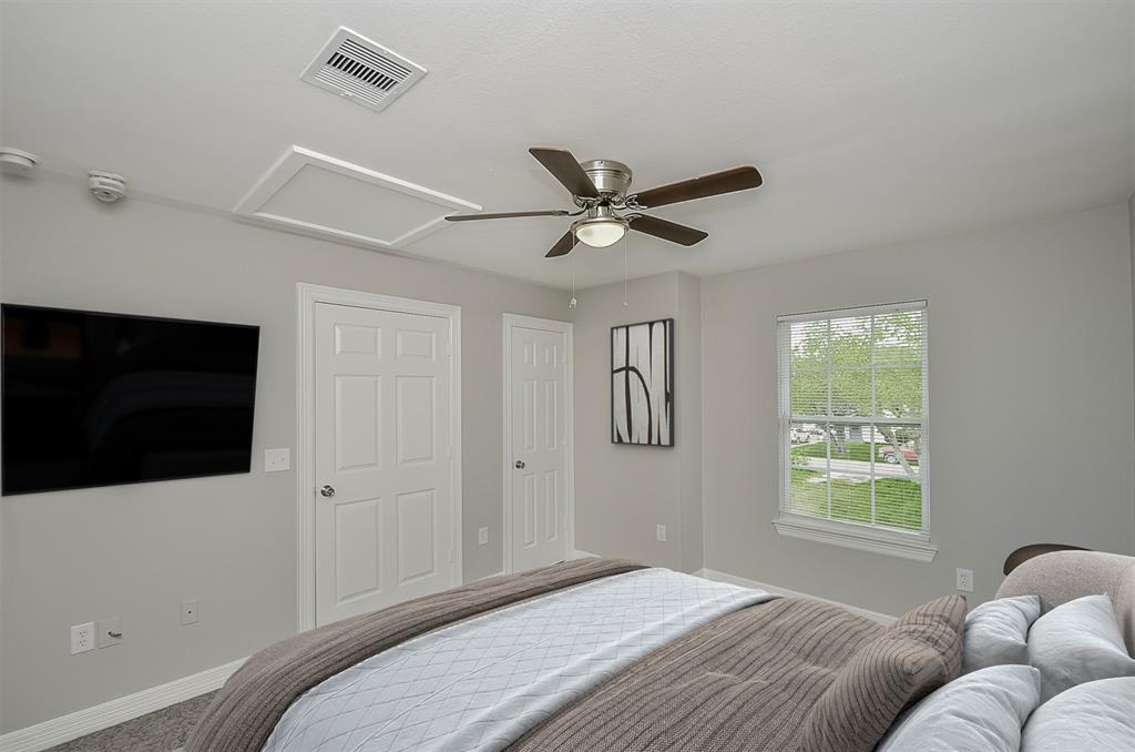 Empty room with tan carpet, a ceiling fan, nd a window overlooking the lawn.