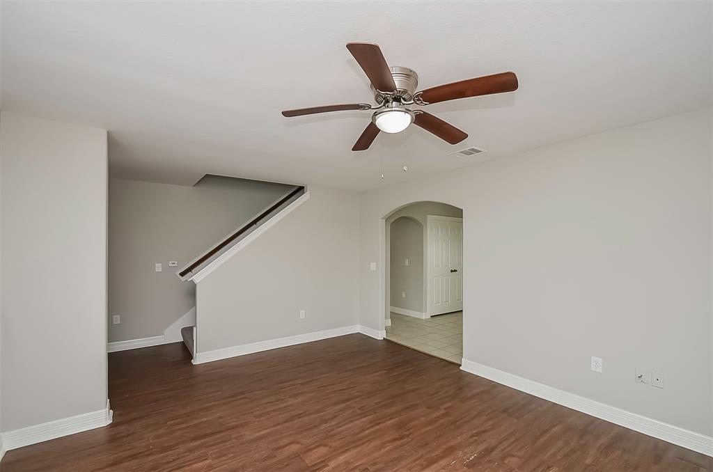 The living room has laminate flooring, neutral walls, a ceiling fan, and stairs leading up to another level.