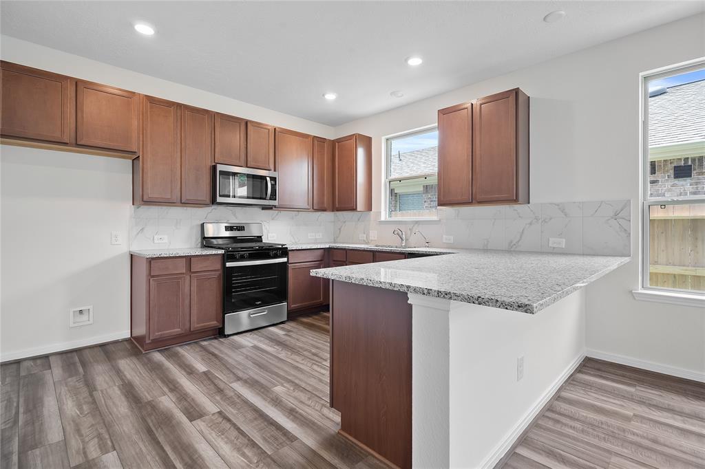 This kitchen is by far any chef’s dream! This spacious kitchen features large windows, high ceilings, stained wood cabinets, granite countertops, SS appliances, modern tile backsplash, recessed lighting, extended counter space, granite kitchen island with double sink and space for breakfast bar, and a walk-in pantry all overlooking your huge family room.