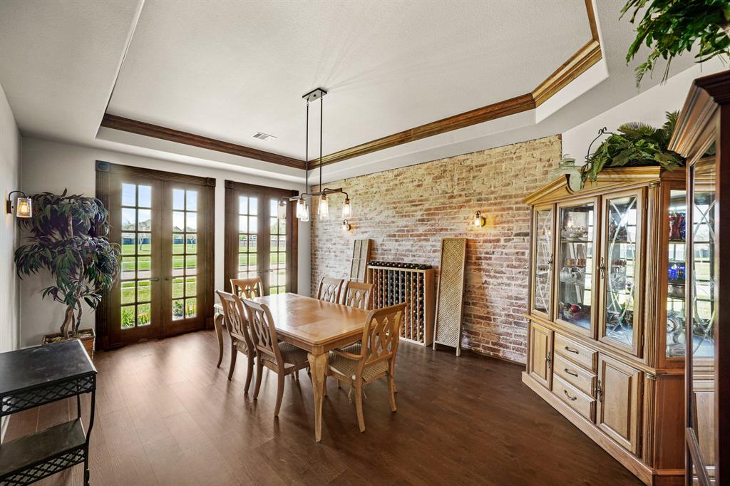 Dining room with brick accent wall and beautiful accent doors overlooking the front.