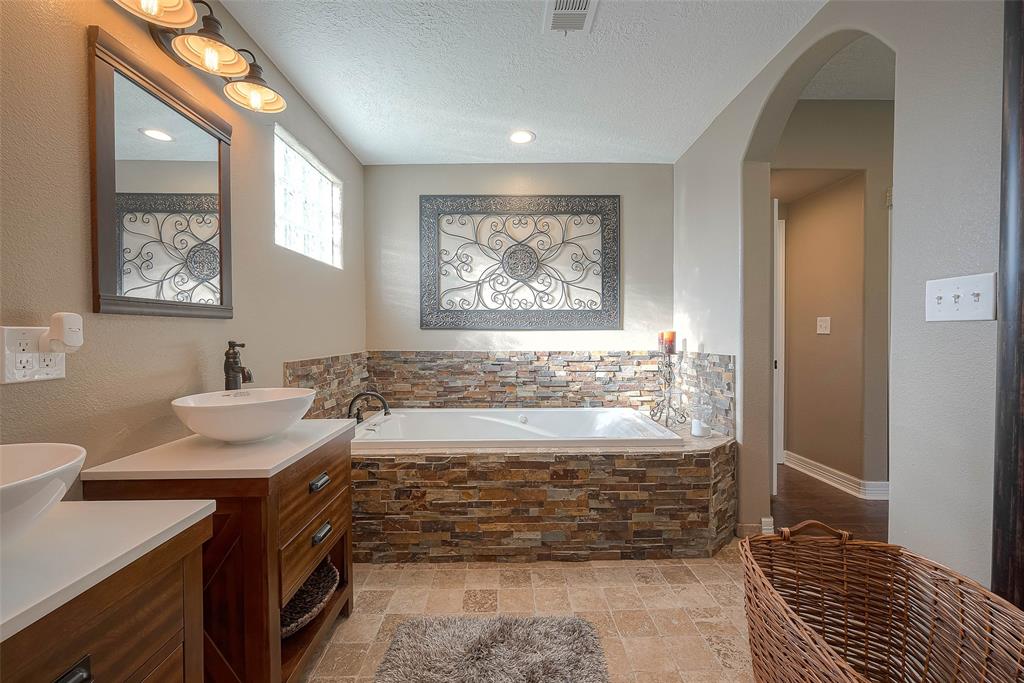 This luxurious primary bathroom is the perfect place to relax and unwind after a long day. An oversized garden tub invites you to soak away your troubles, while his and hers sinks and mirrors provide ample space for two to get ready in the morning.