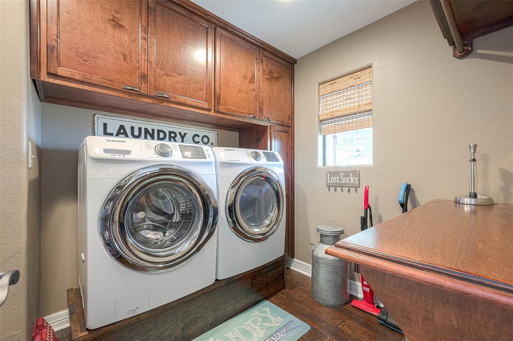 Utility room in house provides ample space for full size washer and dryer, with additional cabinets and space for storage, and putting away laundry