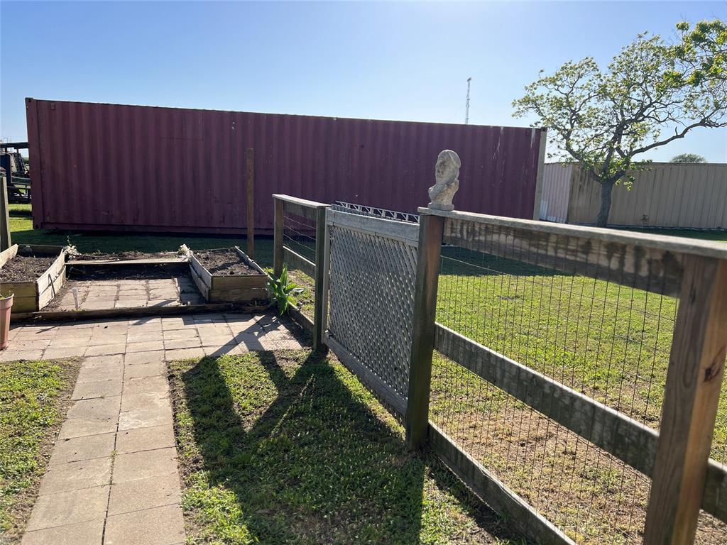 Partially fenced back yard, path to raised garden beds, a shipping container that is negotiable, or the owner will remove.