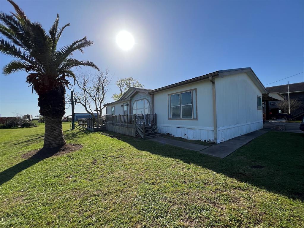 The right front corner of the home showing the wooden porch and a palm tree.