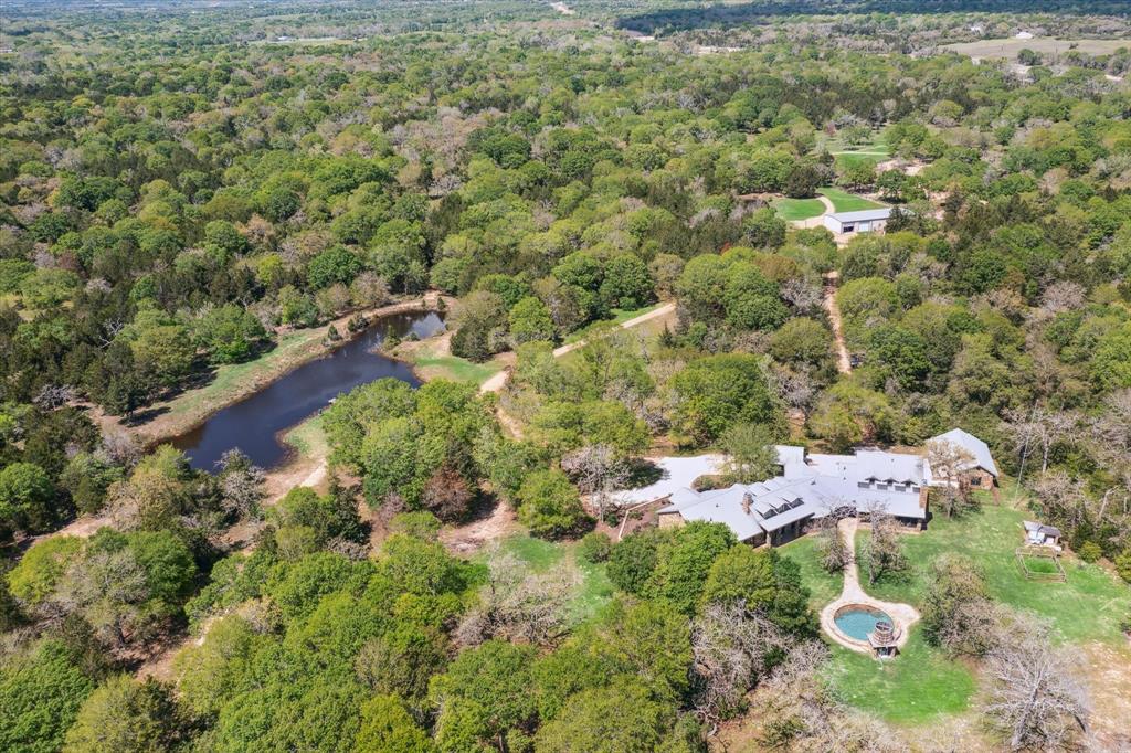 120 AC in the heart of Austin County. The home is a masterpiece of craftsmanship and old-world character. Natural materials and quality finishes define this 5,200 sq. ft. home. The kitchen is peerless, 10 ft. grainery wood island, Chicago brick wall, wine fridge, copper hood/sink, walk in pantry and breakfast nook. Primary has a flex room and ensuite bath, walk in closet and jetted soaking tub for a spa like experience. The guest wing has a family room, loft area and sliding doors opening to the screened in porch with a wood burning fireplace. Bonuses, travertine floors, vaulted ceiling with hand hewned beams, hand carved French Oak floor, porte cochere and pool. The land's beauty and privacy harmonize nature and a relaxed lifestyle. Enjoy fishing or hiking or other recreational uses.The barndominium has full living quaters/lots of storage/work space. Property is truely a world of its own at every turn and all within a short jaunt to Houston and close to the Historic Town of Bellville.