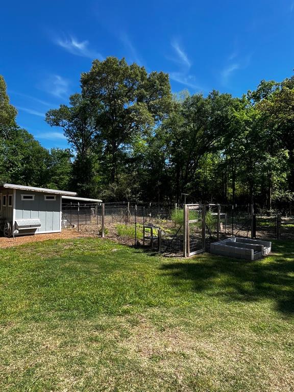 The fenced garden is beside the chicken coop.