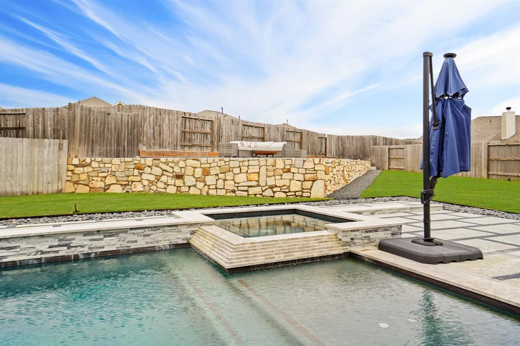 Elevate your outdoor experience with a captivating elevated patio space, backed by a sturdy stone wall that adds charm to your backyard retreat.