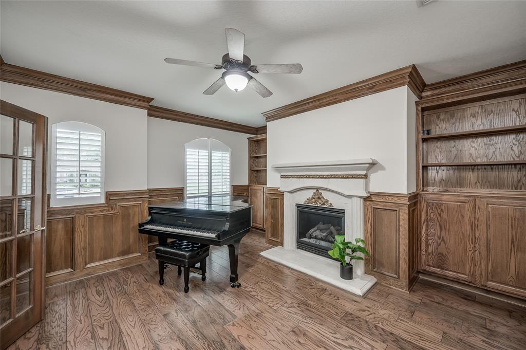 Study/Home Office is located at the front of home and features a stately gas-log fireplace, built-in custom cabinetry, arched windows with plantation shutters, and French doors to provide privacy.