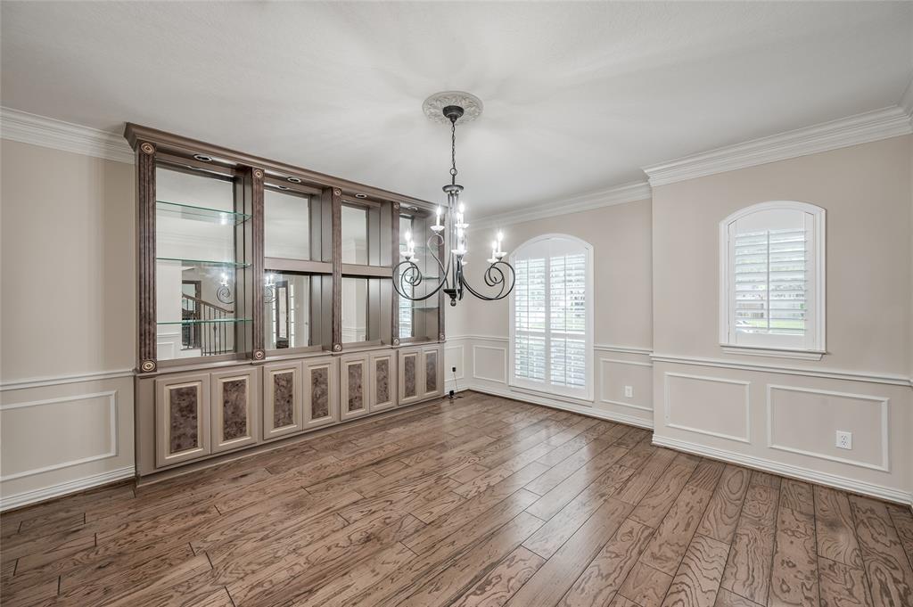 Enjoy large family gatherings in the spacious formal dining room featuring built-in cabinetry, arched windows, classic crown and chair molding, and dazzling wrought-iron chandlier.