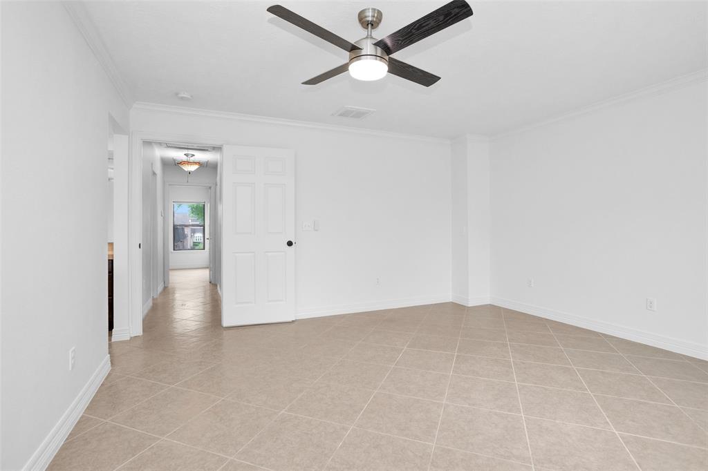 Large & Bright Primary Bedroom features tile flooring for easy upkeep, updated ceiling fan & crown molding.