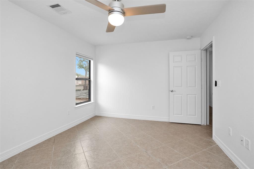 Bedroom #3 features calm neutral tones, tile floors, & an updated ceiling fan.