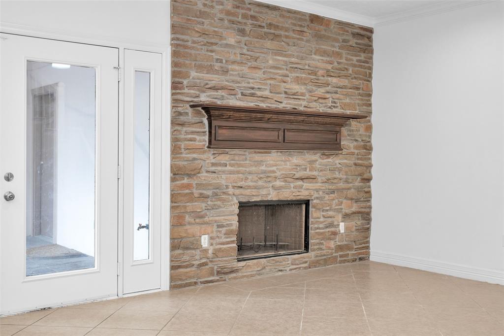 Family Room w/ neutral tones features a cozy wood-burning fireplace. Full-Paned French Door provides access to the to the covered back Patio & creates a great indoor/outdoor flow.