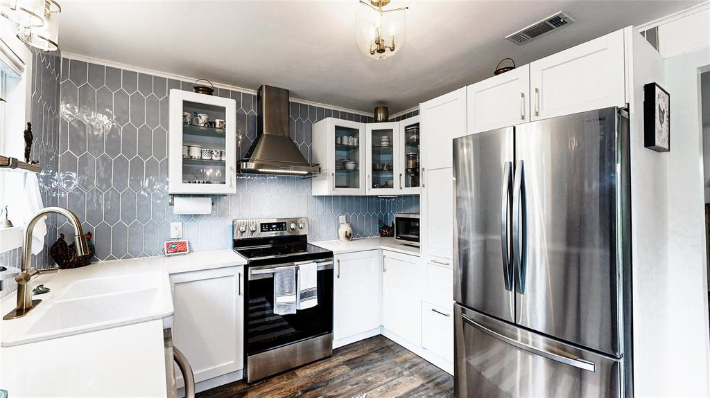 Bright white quartz countertops and cabinets, with stunning grey tile backsplash. All Stainless Steel appliances, and decorative gold pulls all add to the beauty of this kitchen.