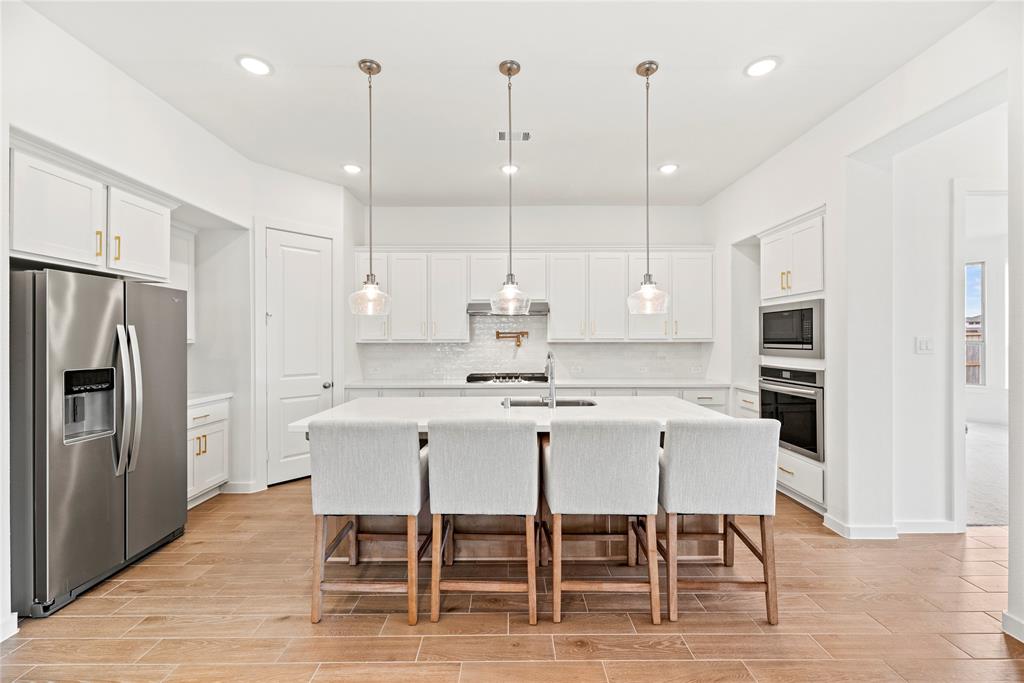 Your chef inspired kitchen awaits! Features include quartz countertops paired with a coordinating backsplash, Stainless Steel appliances, crisp white cabinets with updated hardware, under cabinet lighting, recessed lighting, and a sprawling island with breakfast bar seating.